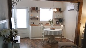 A dining area with a round table, chairs, and a small side table with a basket. - Tranquil 1-bedroom cottage in the pines in Mount Enterprise (Mount Enterprise)