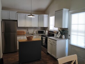 A kitchen with white cabinets, a stainless steel refrigerator, a microwave, and a sink.