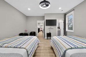 A hotel room with two beds, a TV, a desk, and a window. - Beautiful 5-bedroom house in welcoming Fort Washington (Fort Washington)