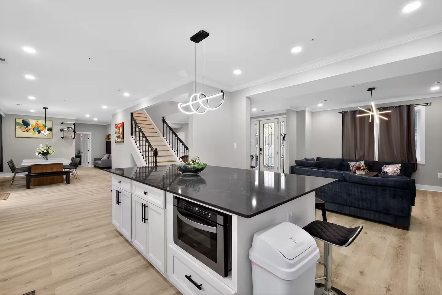 A modern kitchen with a central island, built-in oven, and white cabinetry.