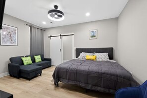 A bedroom with a bed, a sofa, a ceiling fan, and a door. - Beautiful 5-bedroom house in welcoming Fort Washington (Fort Washington)