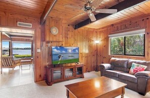 Una habitación con paneles de madera, un televisor, un sofá y una mesa de centro.