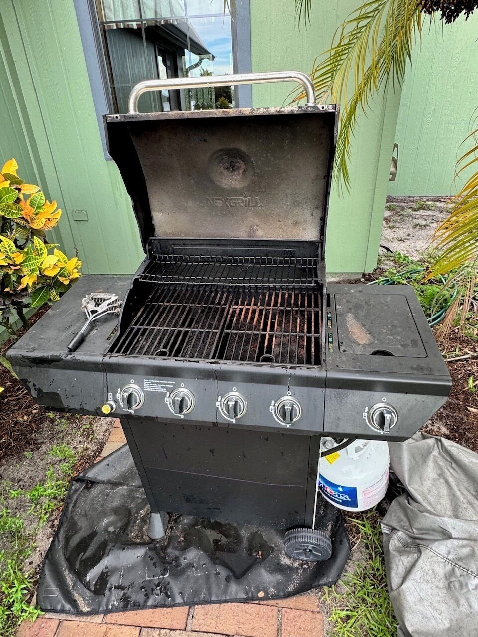 Een barbecue met vier branders, een extra brander ernaast en een deksel.