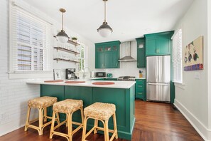 A kitchen with a central island, green cabinets, and a stainless steel refrigerator. - Mint Julep Residence @ Smalls Alley w/ Heated Saltwater Pool (Charleston)