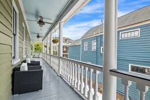 A covered porch with wicker furniture, a ceiling fan, and hanging planters. - Mint Julep Residence @ Smalls Alley w/ Heated Saltwater Pool (Charleston)