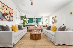 A modern living room with two sofas, a coffee table, and a kitchen in the background. - Mint Julep Residence @ Smalls Alley w/ Heated Saltwater Pool (Charleston)