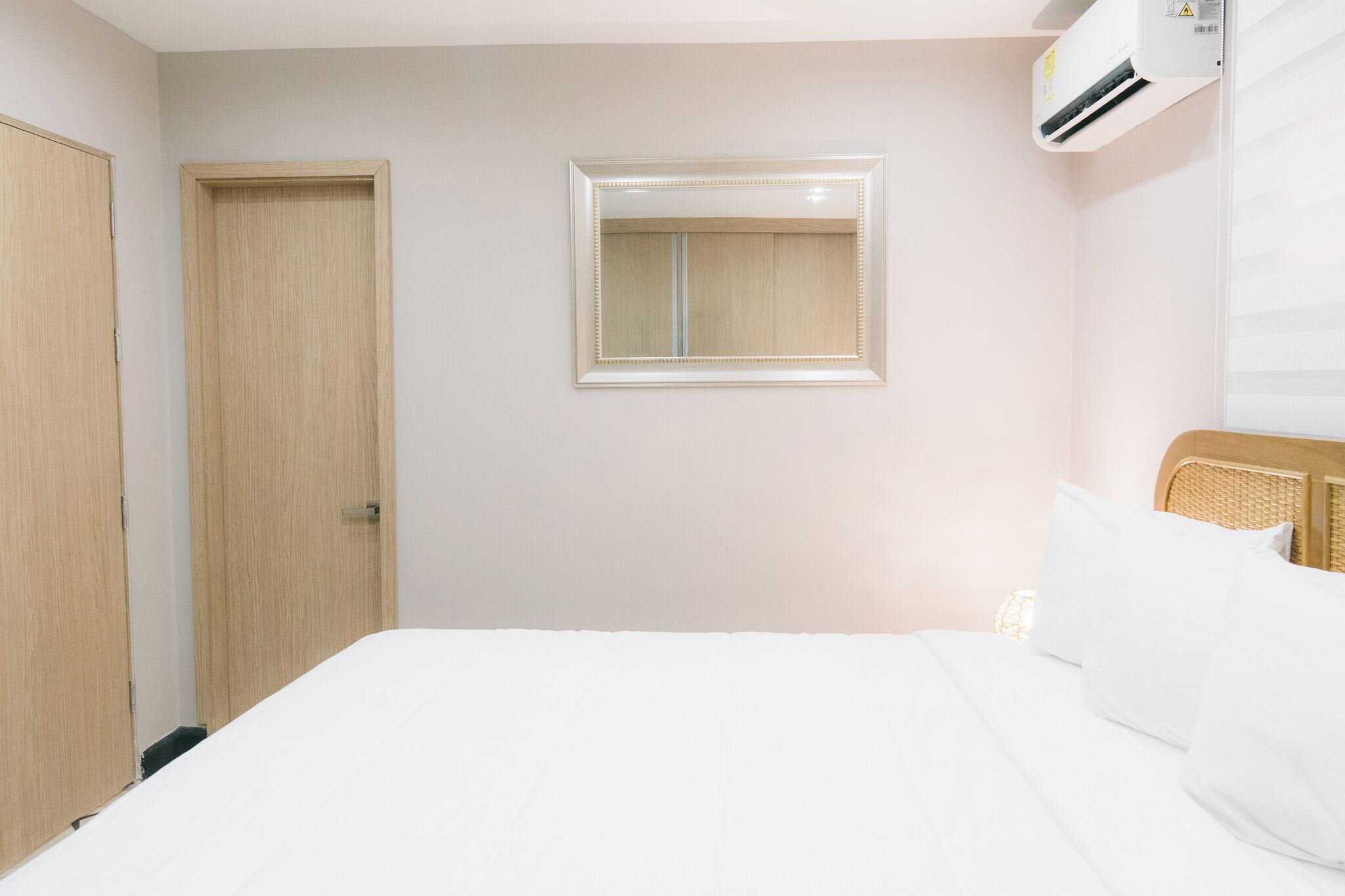 Ein Hotelzimmer mit einem Bett, einem Kleiderschrank, einem Fenster mit Jalousien und einer Klimaanlage.