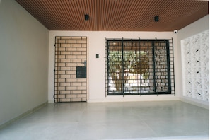 Une pièce dotée d’un sol carrelé, d’un plafond en bois, d’une cloison en briques et d’un panneau mural décoratif blanc.