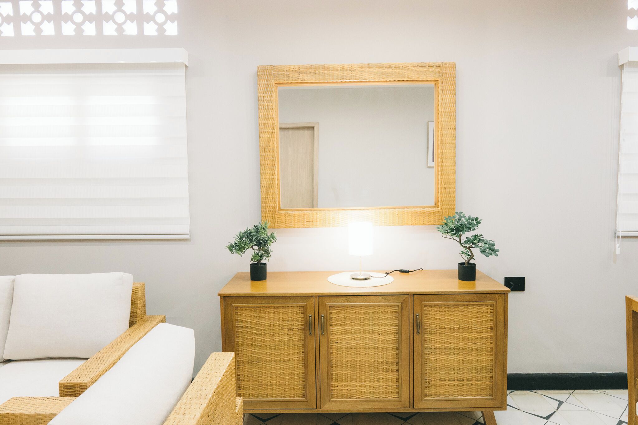 Une chambre à coucher avec un lit, une commode en bois dotée d’un miroir et deux plantes en pot.