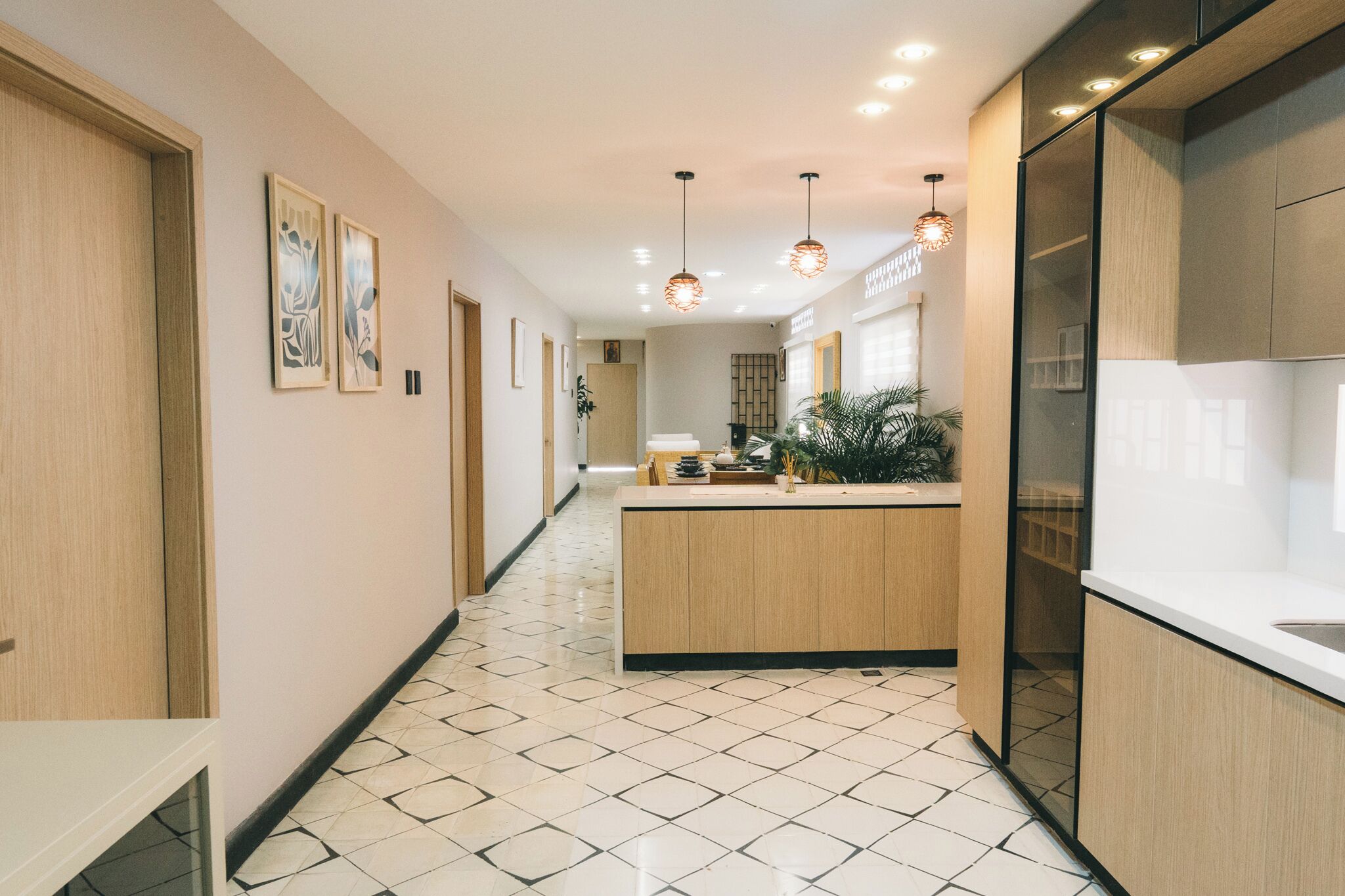 A modern kitchen with a central island, pendant lighting, and a tiled floor.