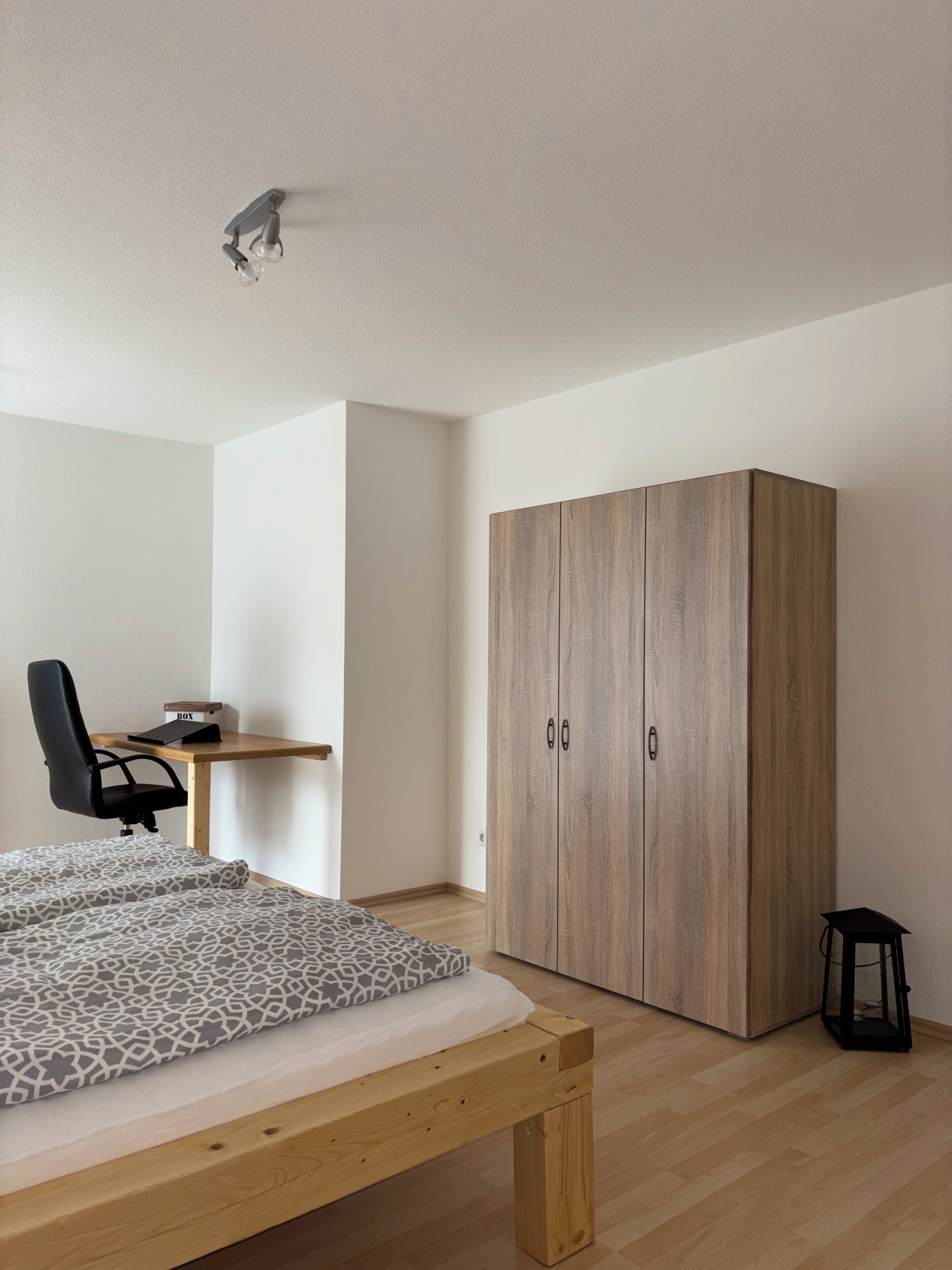 Ein Schlafzimmer mit einem Bett, einem Schreibtisch, einem Stuhl und einem Kleiderschrank.