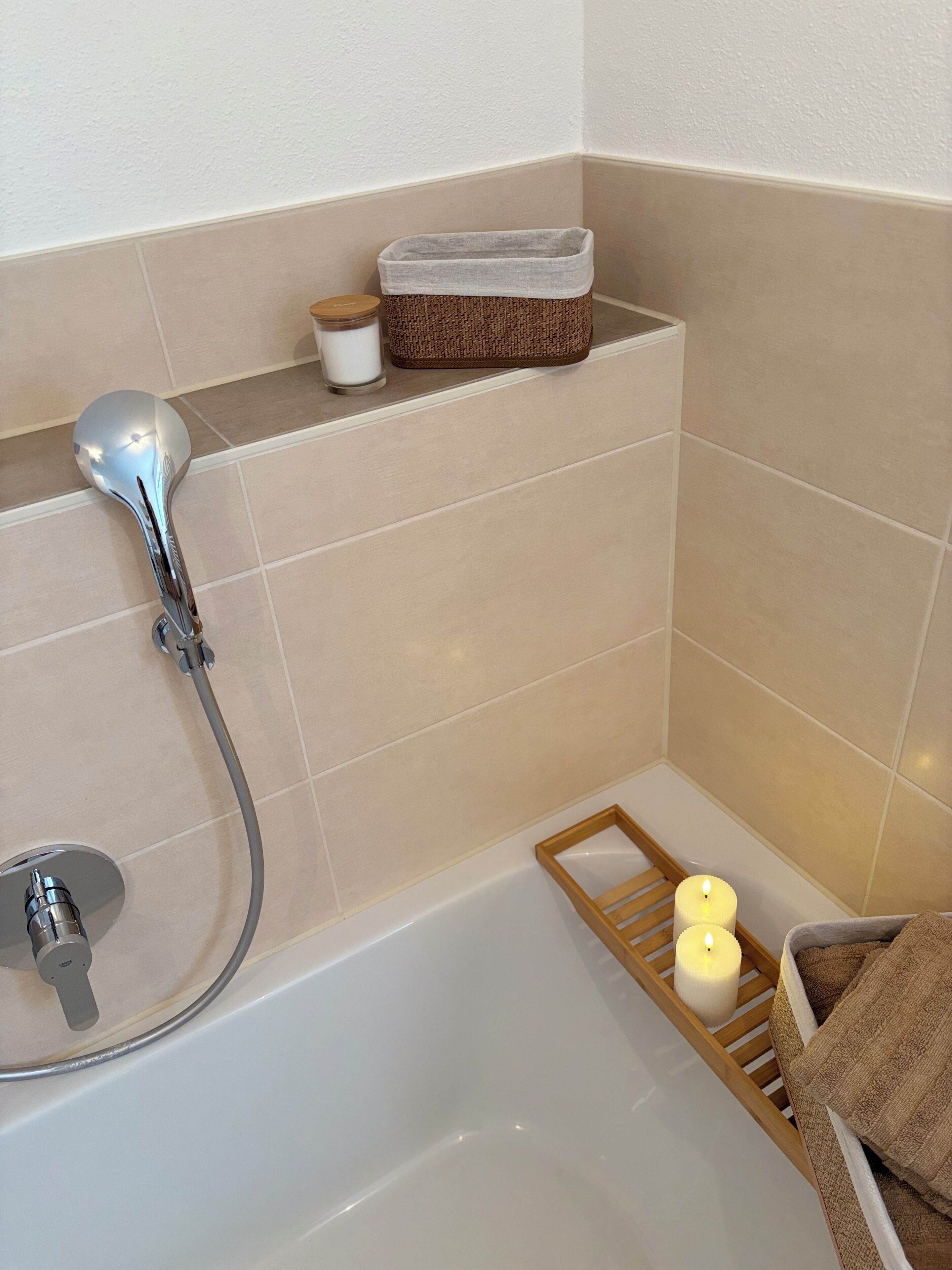 Ein Badezimmer mit Badewanne, Duschkopf, Kerze und Handtuchhalter.