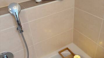 Ein Badezimmer mit Badewanne, Duschkopf, Kerze und Handtuchhalter.