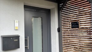Un ingresso moderno con una porta grigia, una cassetta delle lettere e un cartello di benvenuto.