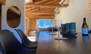 A dining area with a wooden table, wine glasses, and a bottle of wine. - BEAUTIFUL 2-BEDROOM CHALET WITH PANORAMIC MOUNTAIN VIEWS (Lauterbrunnen)