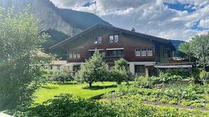 A two-story chalet with a garden in front, surrounded by mountains. - BEAUTIFUL 2-BEDROOM CHALET WITH PANORAMIC MOUNTAIN VIEWS (Lauterbrunnen)