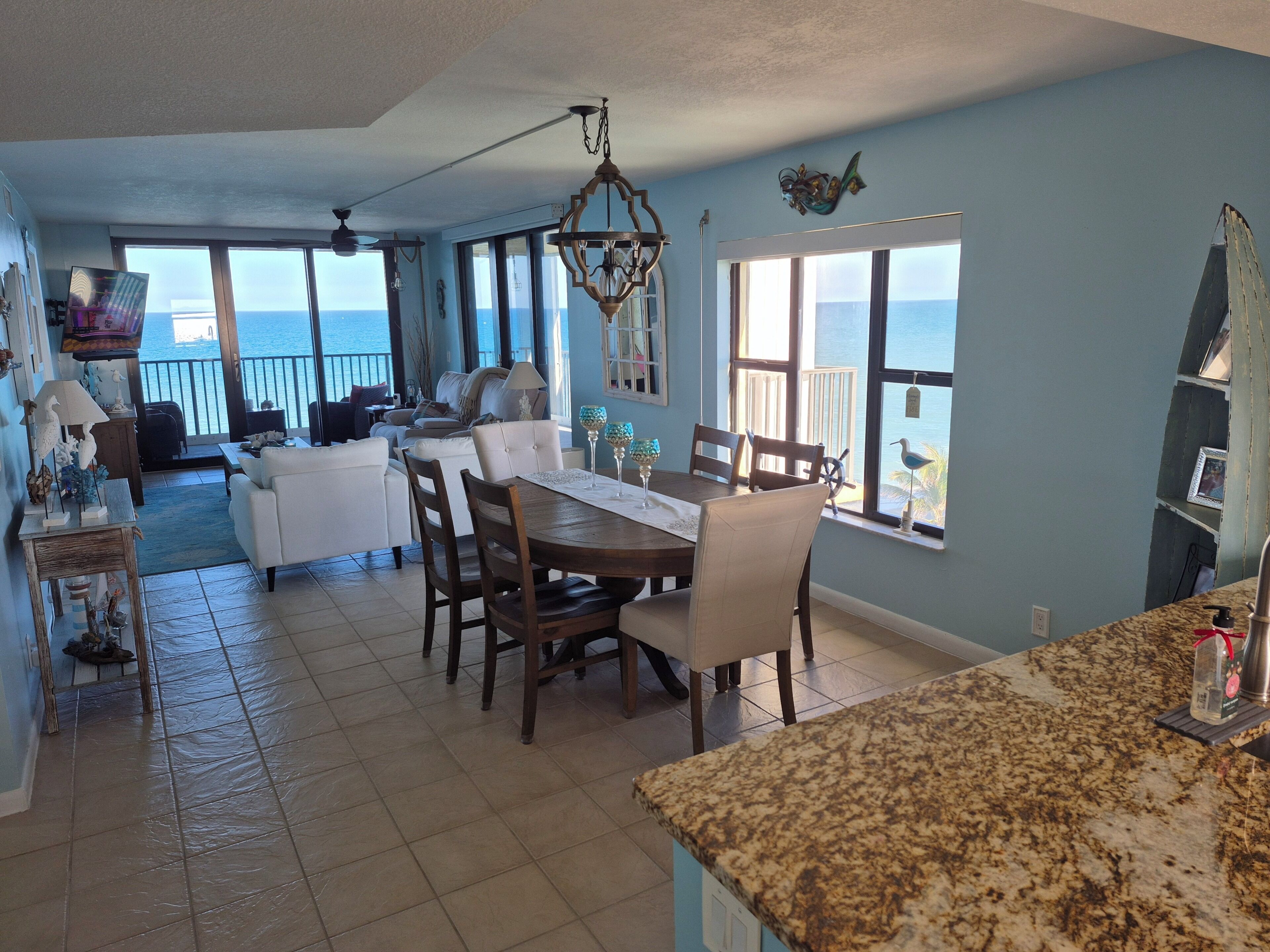 A spacious living area with a dining table, chairs, and a view of the ocean.