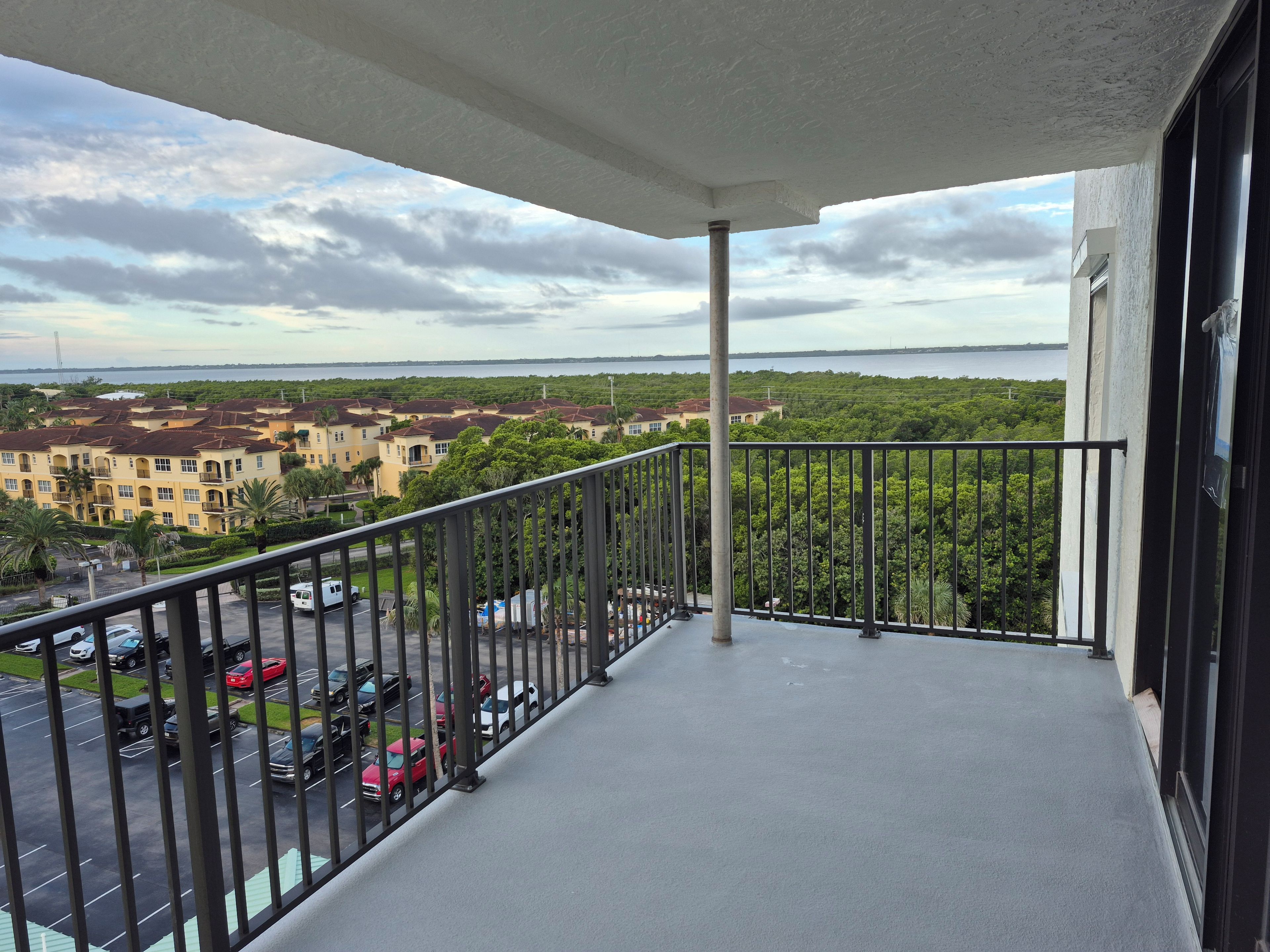 A balcony with a view of a parking lot and buildings.