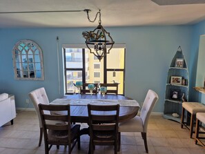 A dining area with a round table, wooden chairs, and a chandelier. - Beautiful Oceanfront condo on scenic Hutchinson Island Florida (Jensen Beach)