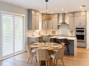 A modern kitchen with a central island, built-in appliances, and a dining area with wicker chairs. - 4-bedroom Sarasota Pool/Spa Retreat. Near Downtown & Beaches (Sarasota)