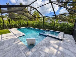 Una piscina interior con techo de cristal, rodeada de exuberante vegetación y vistas al cielo.