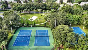 Ein Tennisplatz, umgeben von üppigem Grün und einem kleinen Teich.