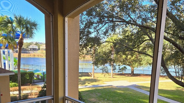 Ein Balkon mit Blick auf einen See, Bäume und ein Gebäude in der Ferne.