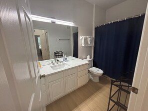 A bathroom with a white sink, mirror, and toilet.