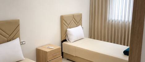 Habitación de hotel con dos camas, una mesita de noche y un diseño moderno en el techo.