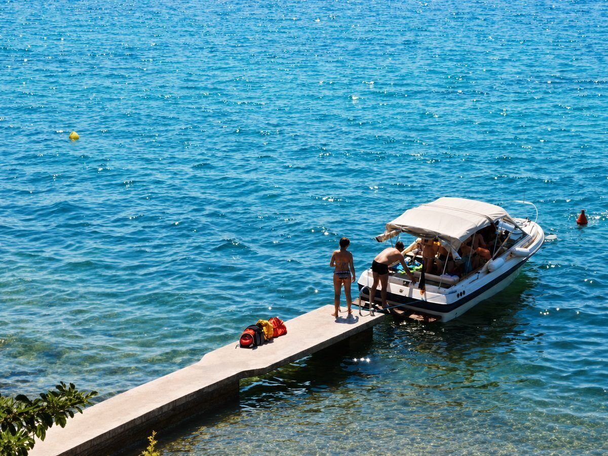 A boat docked at a pier with a clear blue water body.