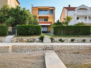 A residential area with a two-story house, a stone pathway, and a cat walking on the path. - Unique villa right on the beach with its own dock. Completely renovated, Zadar (Bibinje)