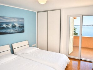 A bedroom with two beds, a sliding door to a balcony, and a painting of the sea on the wall. - Unique villa right on the beach with its own dock. Completely renovated, Zadar (Bibinje)