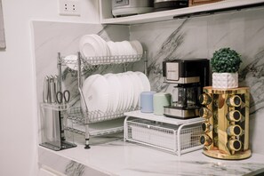 A kitchen counter with a dish rack, coffee maker, and a decorative item.