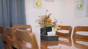Ein Holztisch mit einer Vase getrockneter Blumen und einer Papiertuchbox.