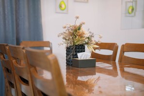 Un tavolo da pranzo in legno con un vaso di fiori secchi e una scatola di fazzoletti.