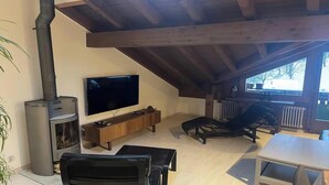 A cozy room with a TV, wooden furniture, a fireplace, and a view of the outdoors. - STUNNING 3-BEDROOM APARTMENT FACING STAUBBACH FALLS (Lauterbrunnen)