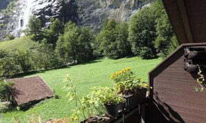 A view of a green lawn with a small building and a waterfall in the background. - STUNNING 3-BEDROOM APARTMENT FACING STAUBBACH FALLS (Lauterbrunnen)