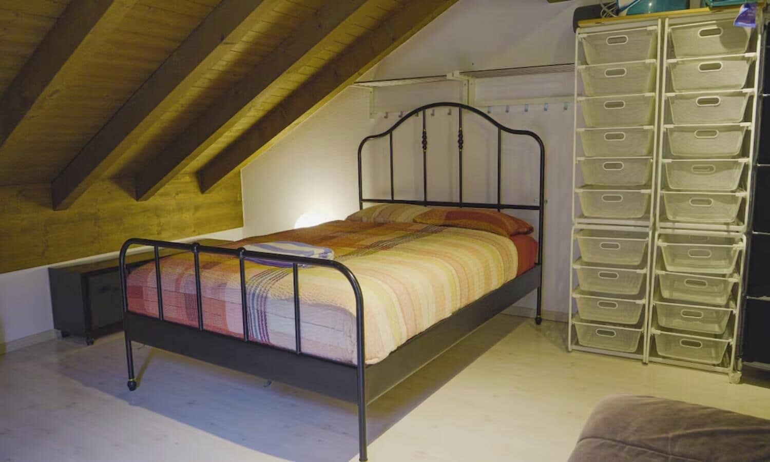 A single bed with a metal frame in a room with sloped wooden ceilings.