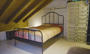 Een eenpersoonsbed met metalen frame in een kamer met schuine houten plafonds.