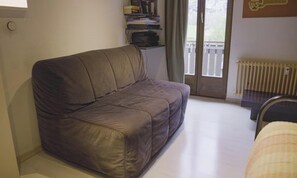 A small, enclosed room with a single brown sofa, a radiator, and a door leading to an outdoor balcony. - STUNNING 3-BEDROOM APARTMENT FACING STAUBBACH FALLS (Lauterbrunnen)