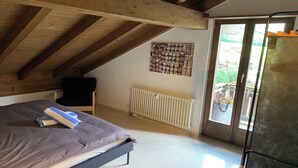 A bedroom with a bed, a radiator, a window, and a door. - STUNNING 3-BEDROOM APARTMENT FACING STAUBBACH FALLS (Lauterbrunnen)