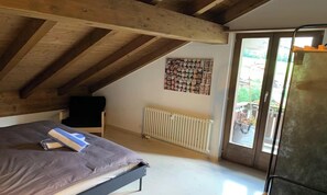 Ein Schlafzimmer mit einem Bett, einem Heizkörper, einem Fenster und einer Tür.