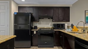 A compact kitchen with dark cabinetry, a black refrigerator, a microwave, and a dishwasher. - So spacious & comfortable ! (Kissimmee)