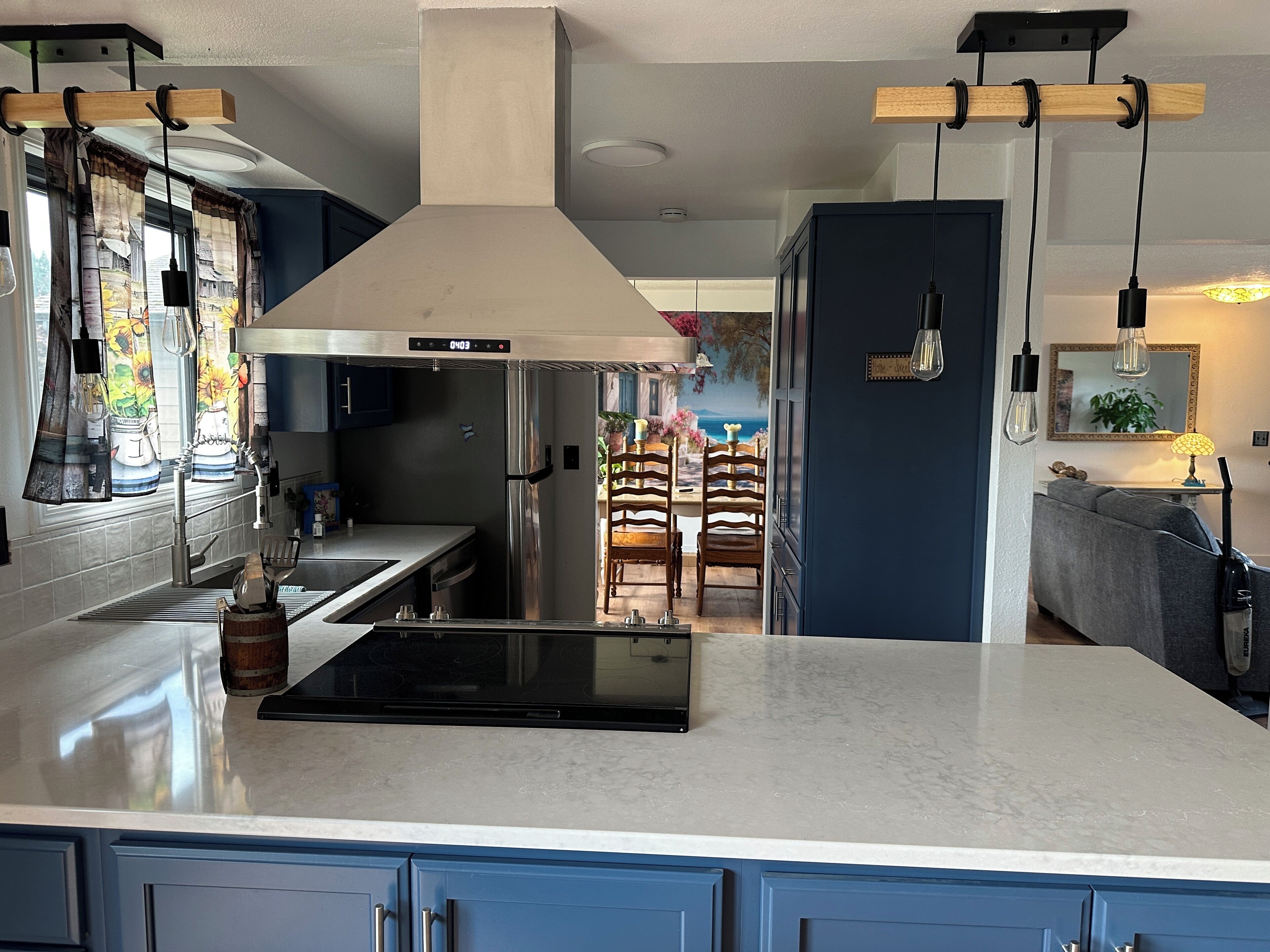 Een moderne keuken met een roestvrijstalen koelkast, een inbouwoven en een groot eiland met een zwart inductiekookveld.
