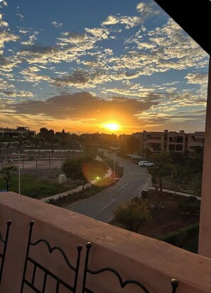 A sunset view from a balcony overlooking a road with buildings in the distance. - 2-bedroom apartment in enchanting Ouahat Sidi Brahim with AC (Ouahat Sidi Brahim)