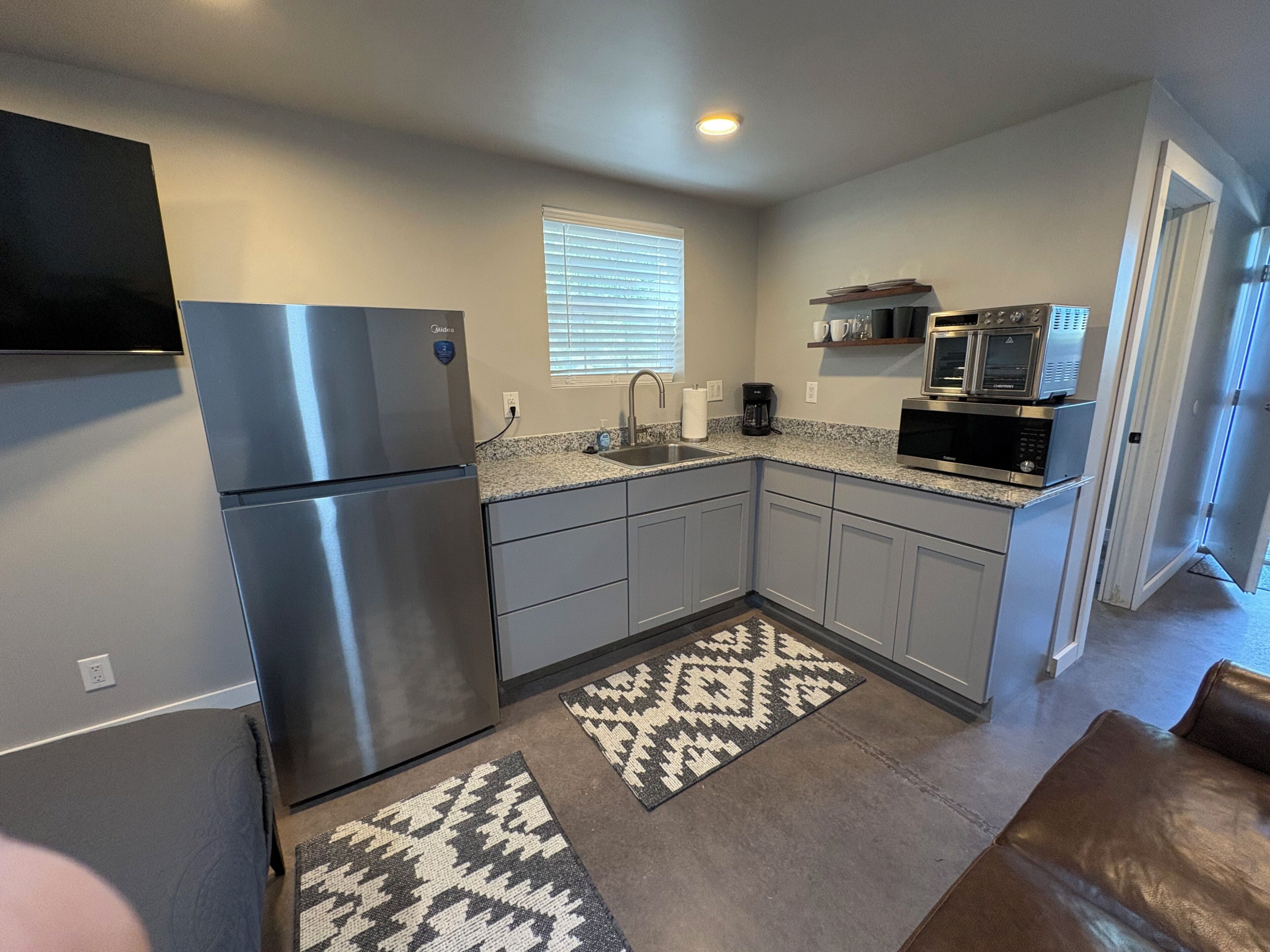 A compact kitchen with a refrigerator, microwave, and coffee maker.