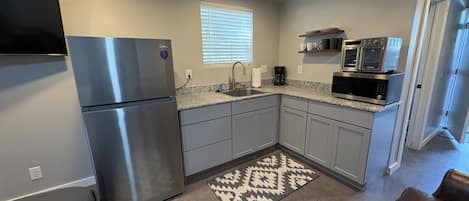 A compact kitchen with a refrigerator, microwave, and coffee maker.