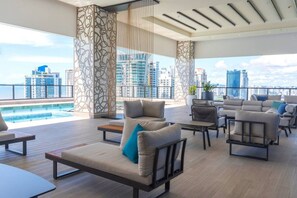 A rooftop lounge with outdoor seating, a pool, and a city view. - Modern Furnished Studio with Ocean Views in Panama U1004 (Panamá)