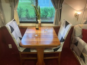 Une table à manger avec des chaises, une bouteille de vin et un verre.