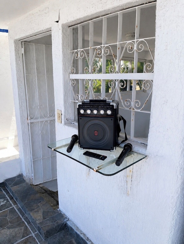 Una estufa de gas portátil sobre una repisa de vidrio frente a un edificio blanco con puerta de metal y ventana.